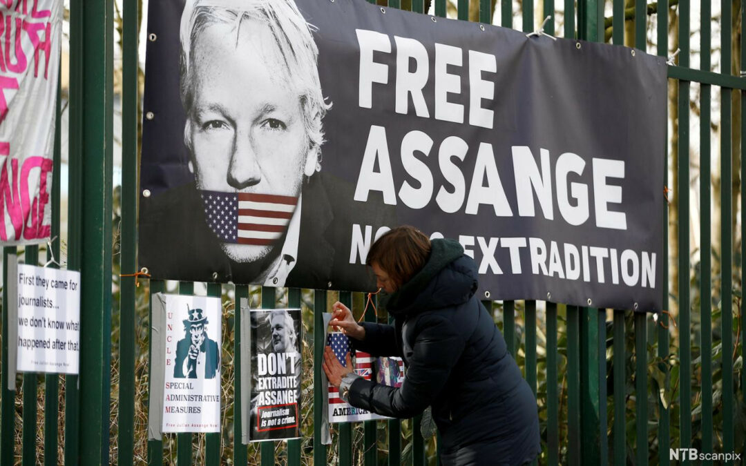 Una donna attacca dei manifesti a favore dei diritti umani di Julian Assange.