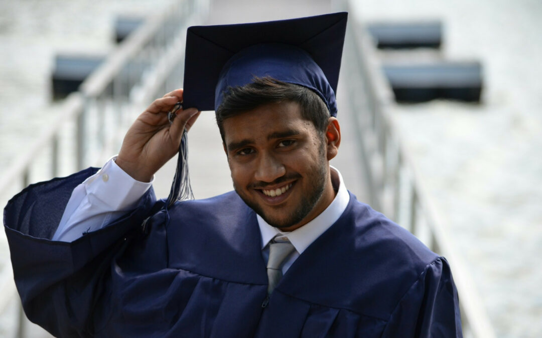 un ragazzo tiene in mano il suo berretto della laurea.